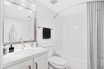 a bathroom with a white sink and toilet and a white bathtub with a shower curtain at Caveness Farms Apartments, North Carolina, 27587